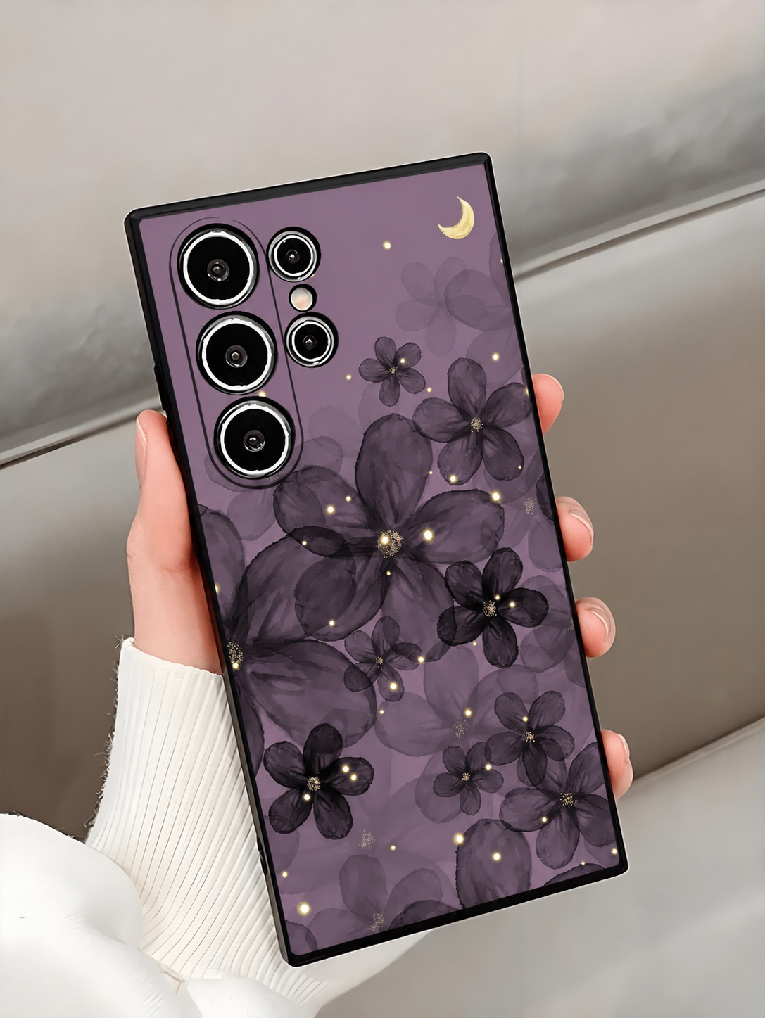 Purple floral moon phone case held beside a white sleeve with short natural nails